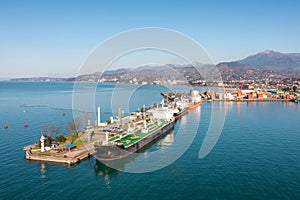 Aerial view industrial cargo and oil port with ship tanker vessel loading in gas and oil terminal station refinery