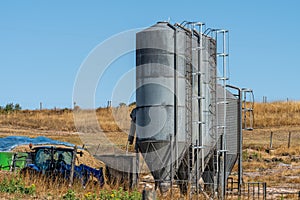 Aerial view of industrial metal silos for product storage and an agricultural tractor