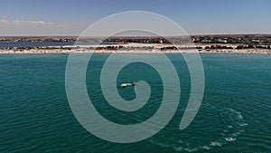 Aerial view of inflatable towed tubes to roll tourists on a tube tied to jet ski across the azure sea on a sunny day