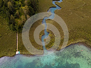 Aerial view on inflow through reeds to Lake `Faaker See` in Carinthia Kaernten, Austria with canoes and a jetty with a