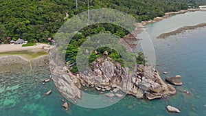 Aerial view of island beach with bungalow and rocky coastline at Haad Khom beach