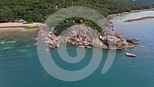 Aerial view of island beach with bungalow and rocky coastline at Haad Khom beach