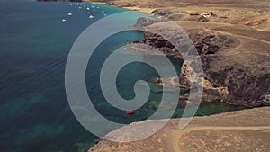 Aerial view of the jagged shores and beaches of Lanzarote, Spain, Canary. Red dinghy moored in a cove. Papagayo
