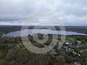 Aerial view of lake Attitash and a town near a shoreline surrounded by colorful trees in autumn