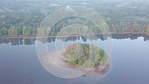 Aerial view of the lake in calm weather in the autumn at sunrise. View from air. Pond, orange grass, trees at dawn. Colorful