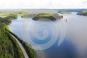 Aerial view of lake with island, road and forest on a summer sunny day in Finland. Drone photography