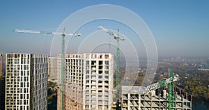 Aerial view of landscape in the city with under construction buildings and industrial cranes. Construction site.