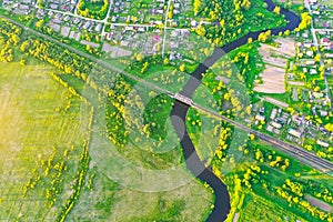 Aerial view landscape of winding small river among the small town, stream in green field meadow, top view