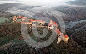Aerial view of the large and beautiful Moravian royal castle Veveri Burg Eichhorn, standing on a rock above water dam on the