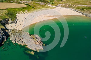 Aerial view of a large, busy sandy beach and rocky coastline in West Wales Broad Haven South, Wales