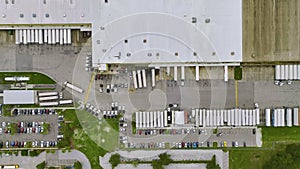 Aerial view of large commercial distribution center with many trucks unloading and uploading retail products for further