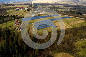 Aerial view of large field of solar photo voltaic panels system producing renewable clean energy on green grass background