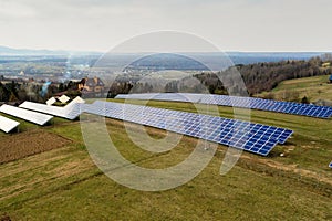 Aerial view of large field of solar photo voltaic panels system producing renewable clean energy on green grass background