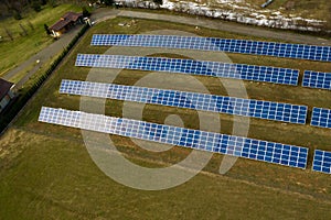 Aerial view of large field of solar photo voltaic panels system producing renewable clean energy on green grass background