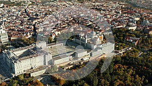 Aerial view of large historic Royal Palace complex at golden hour. Colourful foliage on trees in park of gardens. Tilt