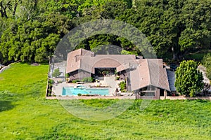 Aerial view of large house with pool surrounded by trees and green meadows, San Jose, Santa Clara county, south San Francisco bay