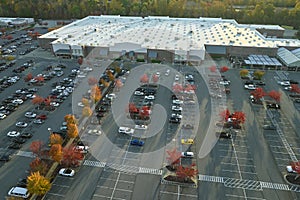 Aerial view of large parking lot in front of rgocery store with many parked colorful cars. Carpark at supercenter