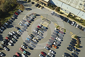 Aerial view of large parking lot in front of rgocery store with many parked colorful cars. Carpark at supercenter