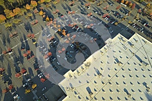 Aerial view of large parking lot in front of rgocery store with many parked colorful cars. Carpark at supercenter