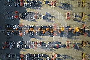 Aerial view of large parking lot with many parked colorful cars. Carpark at supercenter shopping mall with lines and