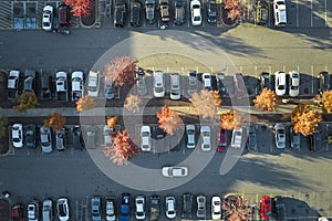 Aerial view of large parking lot with many parked colorful cars. Carpark at supercenter shopping mall with lines and