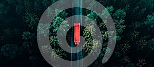 aerial view of large red truck on the road through a green forest. Drone point of view