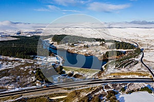 Aerial view of a large reservoir next to a major dual carriageway on a snowy day