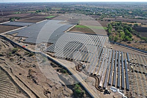 Aerial view of a large-scale solar farm with an array of black solar panels arranged in neat rows