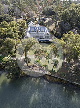 Aerial view of large waterfront luxury home on wooded lot