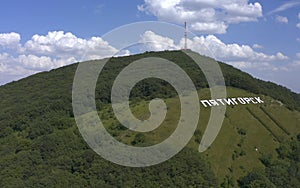 Aerial view of large white letters PYATIGORSK on the green Mashuk mountain