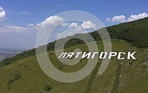 Aerial view of large white letters PYATIGORSK on the green Mashuk mountain