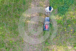 Aerial view of lawn mower cutting green grass in backyard, mowing lawn