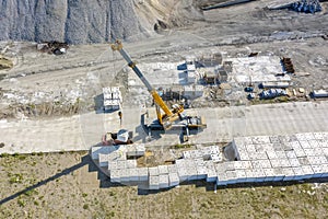 Aerial view of the lifting big concrete blocks for harbor construction by a large crane.