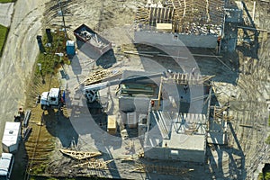 Aerial view of lifting crane and builders working on unfinished residential house with wooden roof frame structure under
