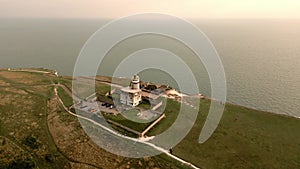 Aerial view of the lighthouse on the edge of a cliff next to the sea.