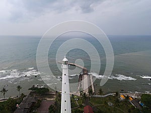 Aerial view of Lighthouse sea rock sunset landscape. Sunset lighthouse scene. At anyer beach with noise cloud and cityscape.