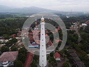 Aerial view of Lighthouse sea rock sunset landscape. Sunset lighthouse scene. At anyer beach with noise cloud and cityscape.