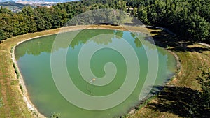 Aerial view of a little lake and trees surrounding, in italian Appennini hills