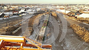 Aerial view of logging train at sawmill hauls stacked wooden logs and tree trunks. Train at the territory of the