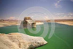 An aerial view of Lone Rock in Lake Powell, blue cloudy skies and green water. Arizona USA