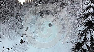 Aerial view on Lonely Car Riding on Snowy Road in Magic Winter Forest