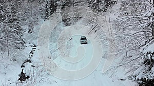 Aerial view on Lonely Car Riding on Snowy Road in Magic Winter Forest