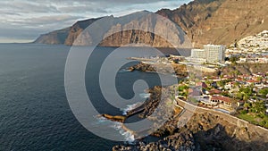 Aerial view of Los Gigantes restort on Tenerife Canary island. Flying over magnificent hotels, villas and natural pool