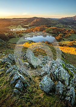 Aerial view of Loughrigg Tarn with morning sunlight on a Winter morning with blue sky. Lake District, UK.