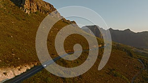 Aerial view of low traffic on road in mountain landscape in sunset time. Golden hour lit scene. South Africa