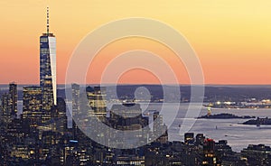 Aerial view of Lower Manhattan skyline illuminated at sunset with orange background in New York City