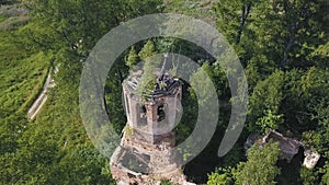 Aerial view of lush forest on a sunny summer day and an old church. Clip. Flying over ruins of the ancient stony church