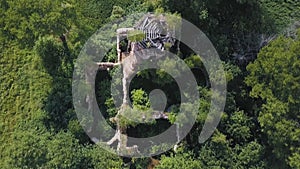 Aerial view of lush forest on a sunny summer day and an old church. Clip. Flying over ruins of the ancient stony church