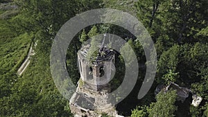 Aerial view of lush forest on a sunny summer day and an old church. Clip. Flying over ruins of the ancient stony church