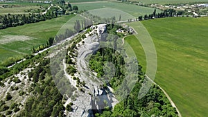 Aerial view of lush green farm field at spring sunny day with rocky cliffs in the distance. beauty of rural areas and